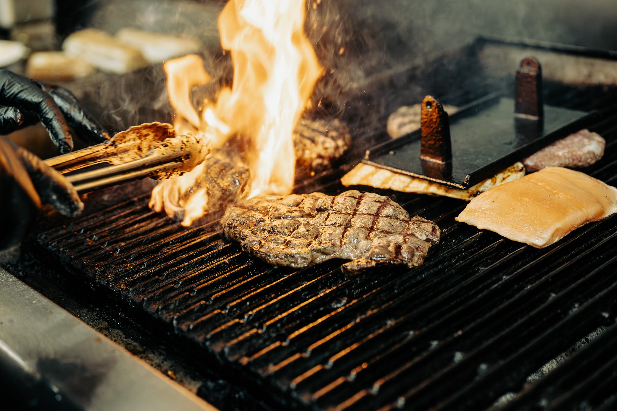 Hand-cut ribeye on the grill with char marks and flames