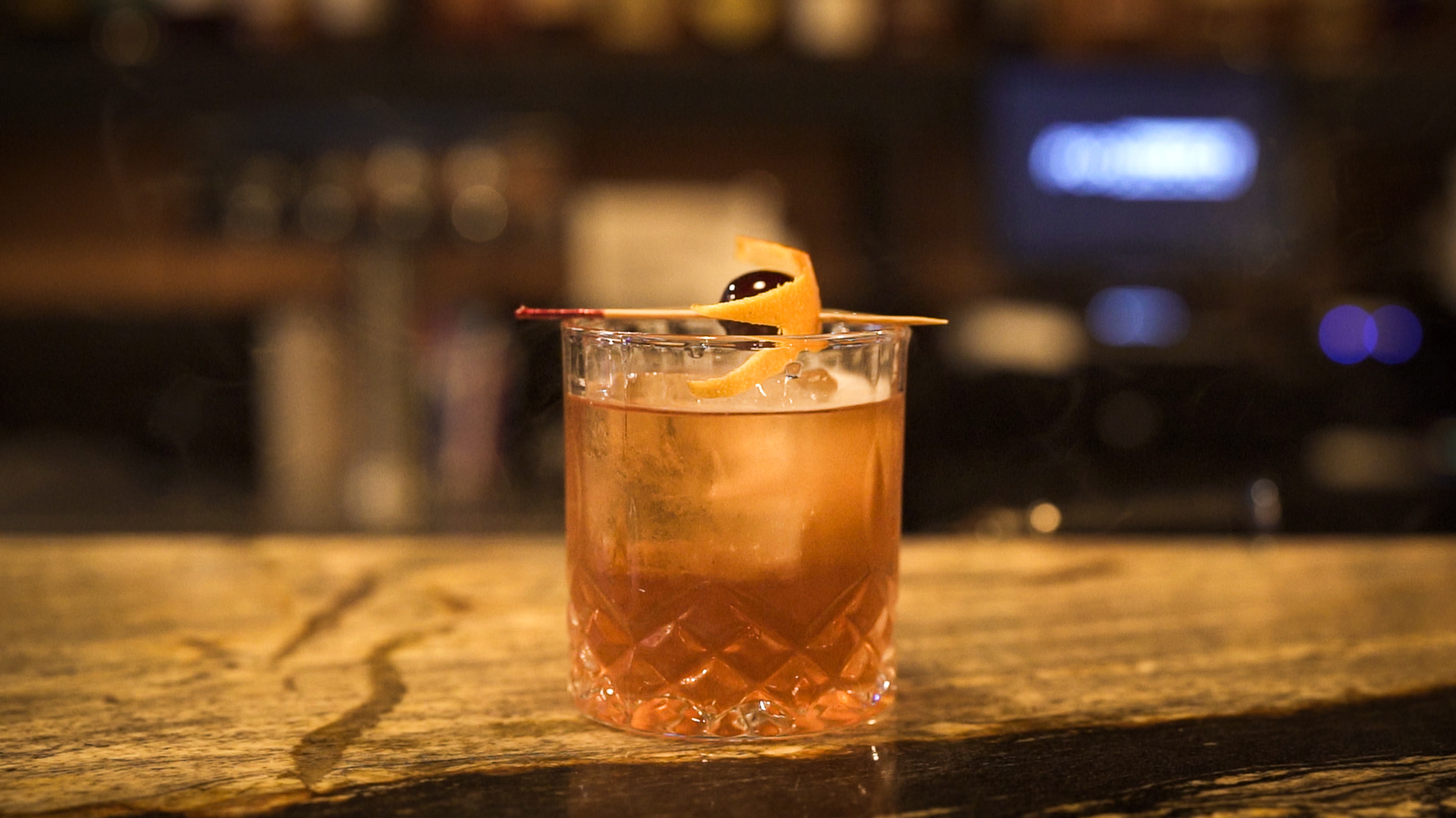 Smoked old-fashioned with bourbon bottle behind it